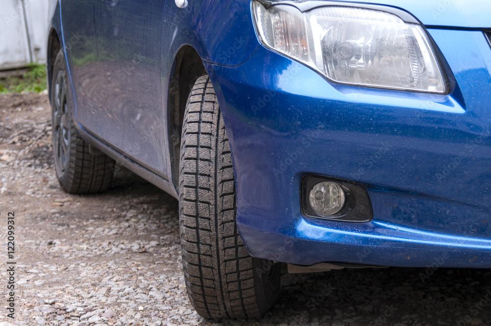Detail of a blue passenger car, wheels and headlights  