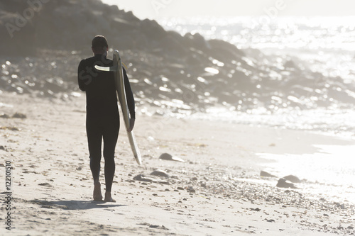 Male surfer walks the beach at sunrise in Long Island  New York