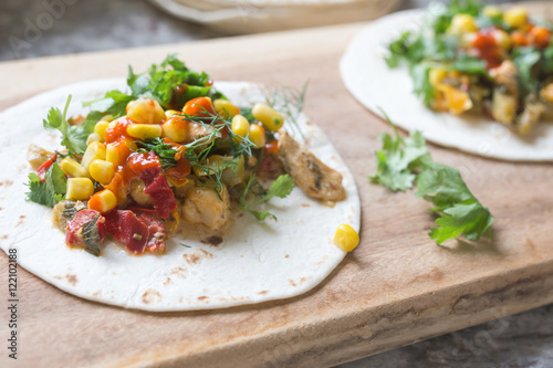 fresh tacos with chicken, vegetables and herbs on a wooden board