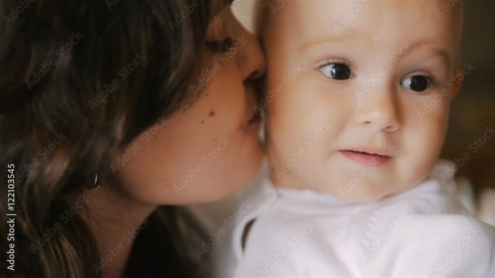 Young Happy Mother Holding her Newborn Child and kissing. Family at home. Beautiful smiling Mom and Happy Baby Together. Tenderness concept. Young Happy Mother Holding her Newborn Child and kissing. Family at home. Beautiful smiling Mom and Happy Baby Together. Tenderness concept.