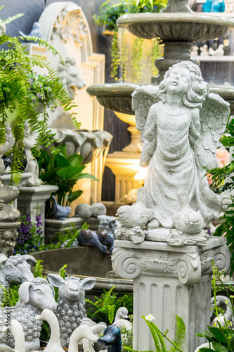 Statue of Cupid in cozy garden./ Statue Cupid and waterfall in cozy garden.