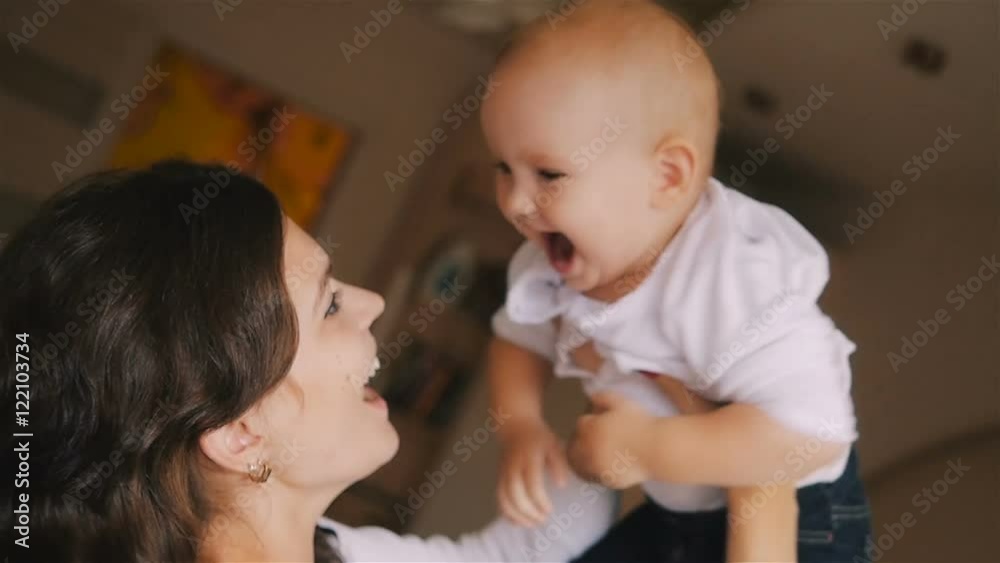 Young Happy Mother Holding her Newborn Child and throws up. Family at home. Beautiful smiling Mom and Happy Baby Together in bed. Young Happy Mother Holding her Newborn Child and throws up. Family at home. Beautiful smiling Mom and Happy Baby Together in bed.
