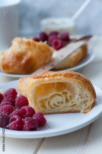 A croissant cut in half served with fresh raspberries. 