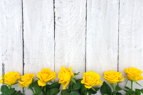 Frame of yellow roses on white rustic wooden background. Valenti