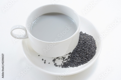 Soya milk and black sesame seeds in cup on white background
