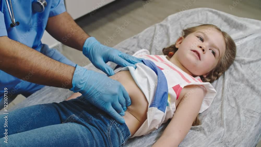 Little girl lying on examination bed and smiling as doctor pressing on her stomach Stock ビデオ | Adobe Stock