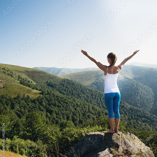 Young woman meditate on the top of mountain