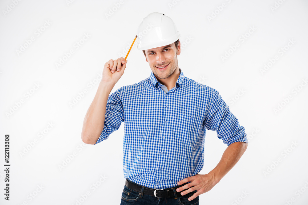 Cheerful man architect in hard hat standing and holding pencil Cheerful man architect in hard hat standing and holding pencil