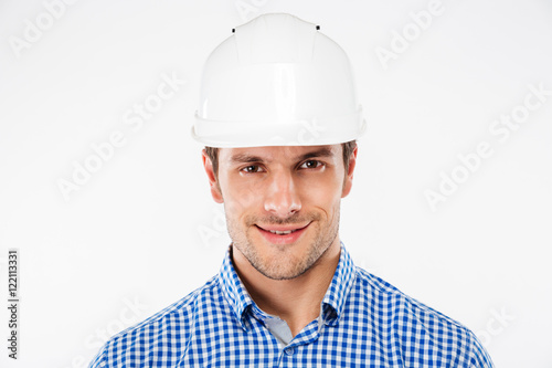 Closeup of smiling young man builder in hard hat