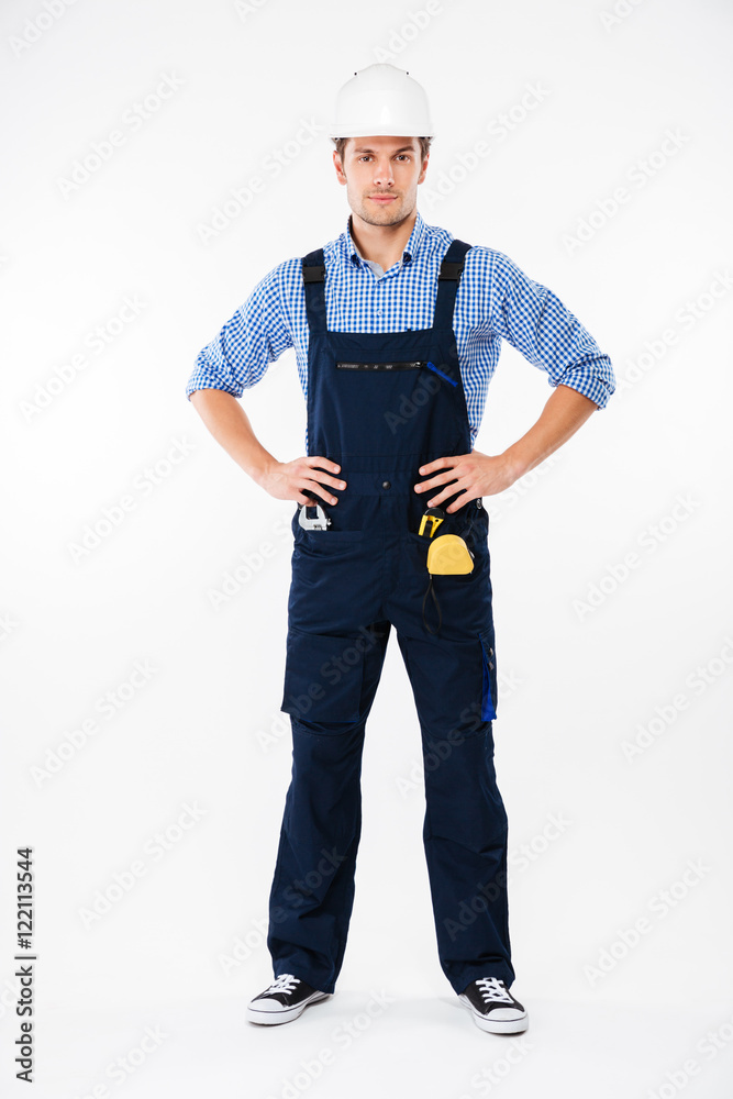 Full length of confident young man builder in helmet standing Full length of confident young man builder in helmet standing