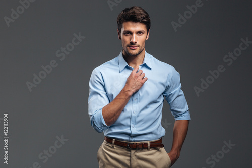 Foto Handsome serious man buttoning his shirt isolated