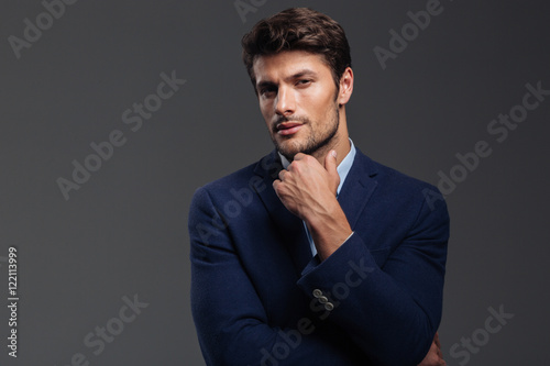 Thoughtful young brunette man in blue jacket thinking about something