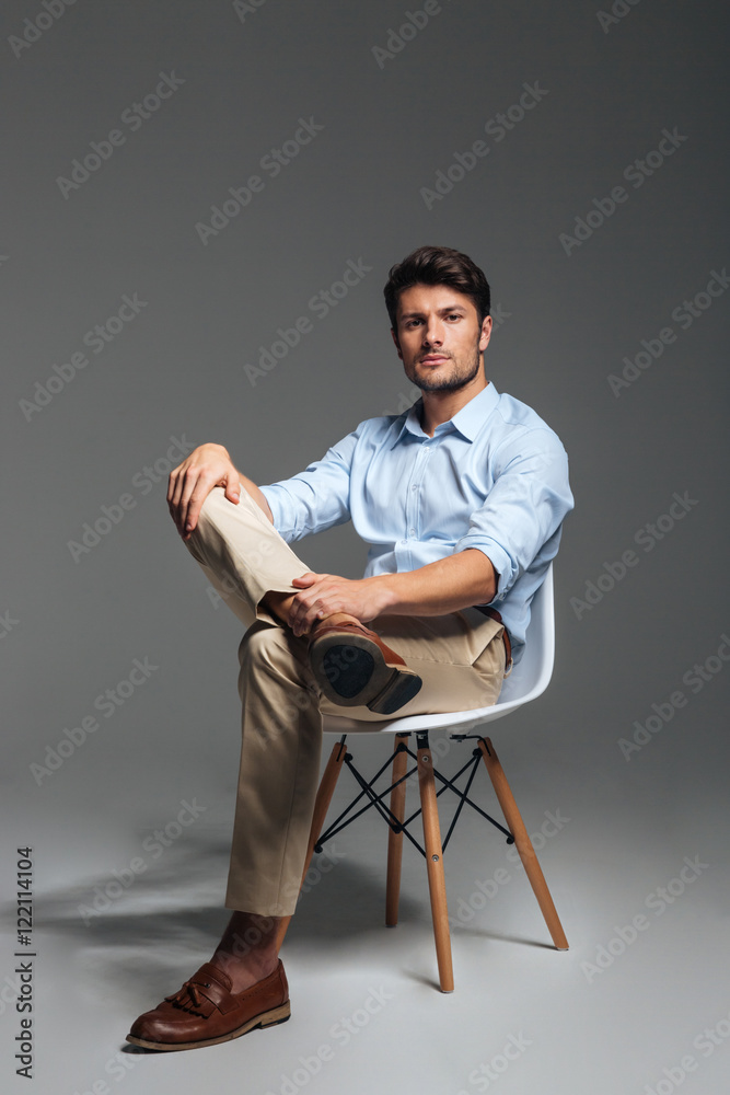 Handsome young confident man sitting on the chair Handsome young confident man sitting on the chair