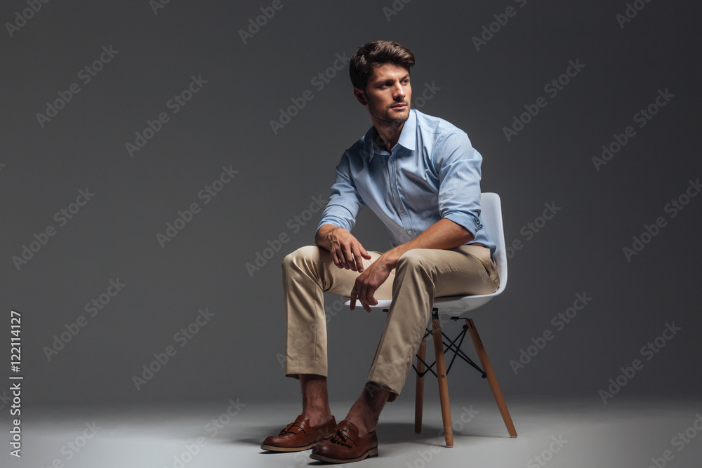 Pensive brunette man in blue shirt sitting on the chair Pensive brunette man in blue shirt sitting on the chair