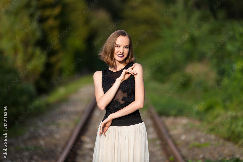 Elegant woman standing on railroad tracks Elegant woman standing on railroad tracks