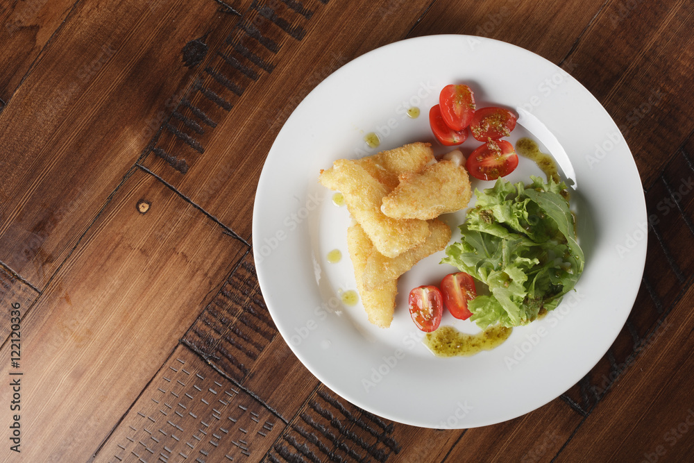 Breaded cheese (deep-fry) with tomatoes and greens in a white plate. Wooden background Breaded cheese (deep-fry) with tomatoes and greens in a white plate. Wooden background