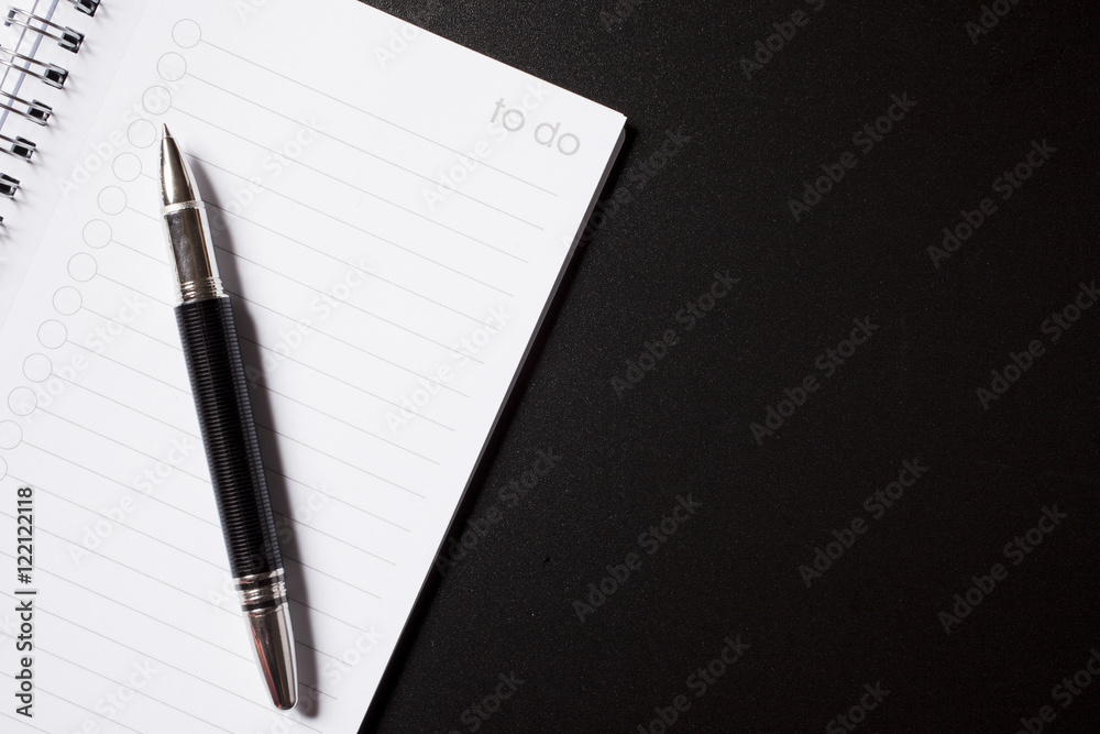 to do list and pen on black background to do list and pen on black background