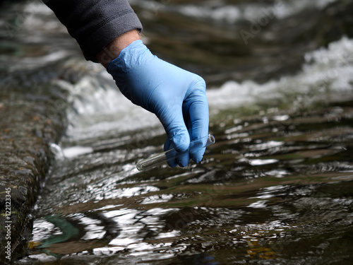 Water sample. Gloved hand into the water collecting tube. Analysis of water purity, environment, ecology - concept. Water testing for infections, harmful emissions