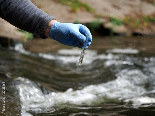 Water sample. Gloved hand into the water collecting tube. Analysis of water purity, environment, ecology - concept. Water testing for infections, harmful emissions