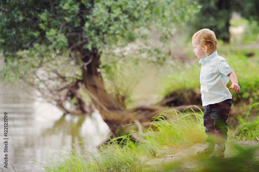 Little blond boy standing on the river Bank, full height, place for text. Little blond boy standing on the river Bank, full height, place for text.