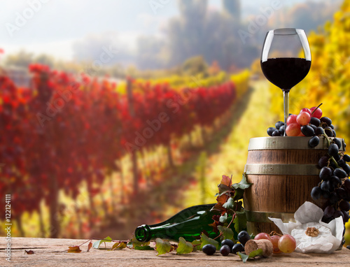 Red wine bottle and wine glass on wooden barrel with nature background