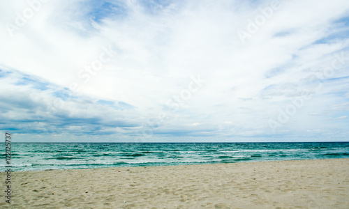 Dark green autumn sea, cloudy sky and a sand beach