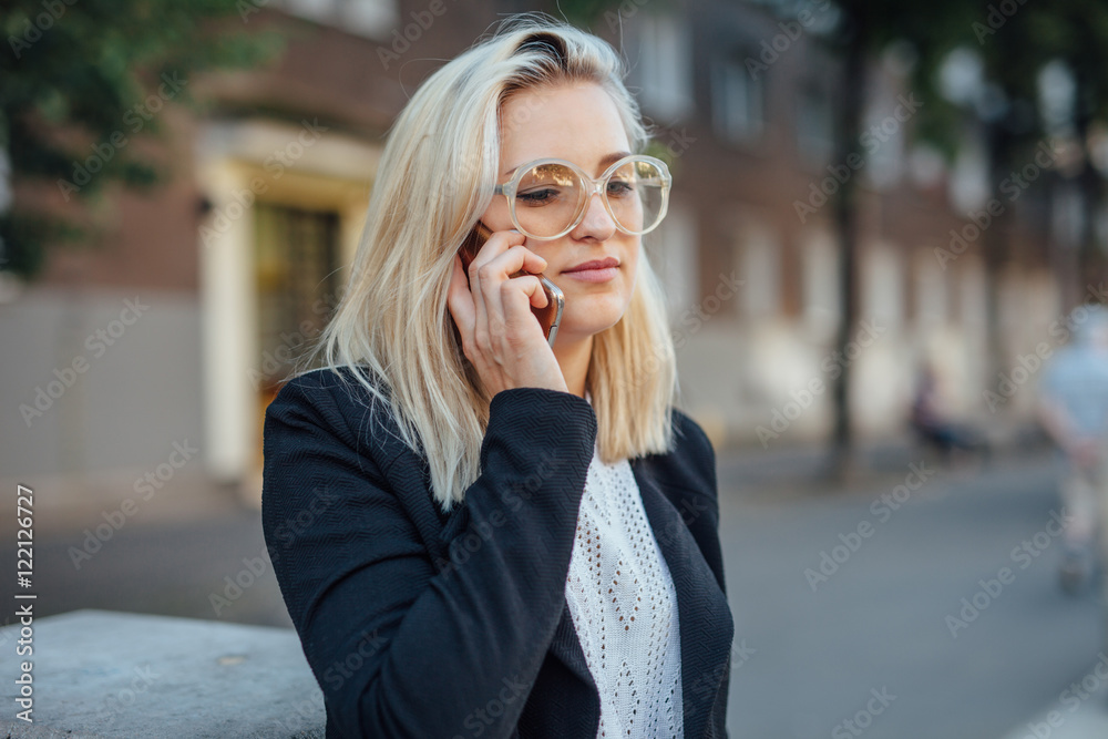 Business woman is talking by the phone. City background.