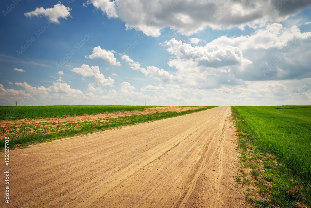 Beautiful landscape with road, green fields and blue cloudy sky Beautiful landscape with road, green fields and blue cloudy sky