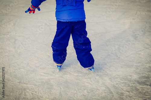 child feet learning to skate on ice in winter
