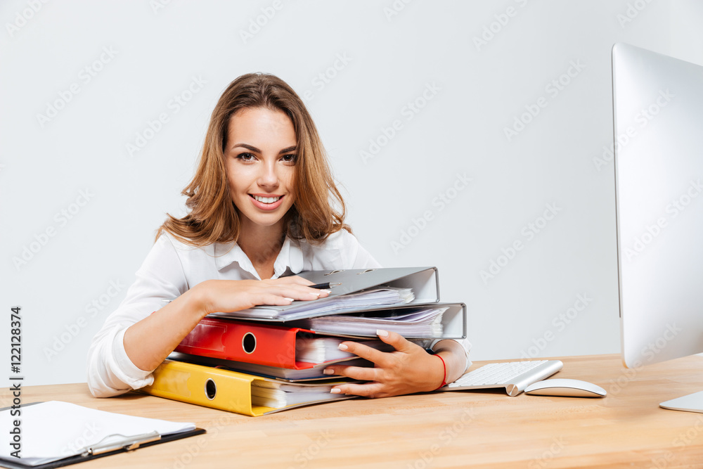 Happy businesswoman holding folders while sitting at the office desk