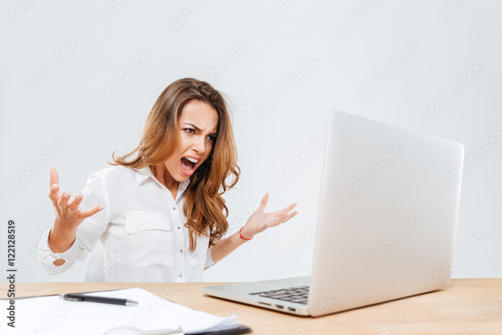 Mad furious young businesswoman using laptop and screaming Mad furious young businesswoman using laptop and screaming