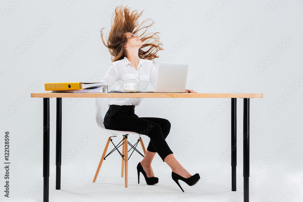 Happy young businesswoman sitting with hair flying in the air Happy young businesswoman sitting with hair flying in the air