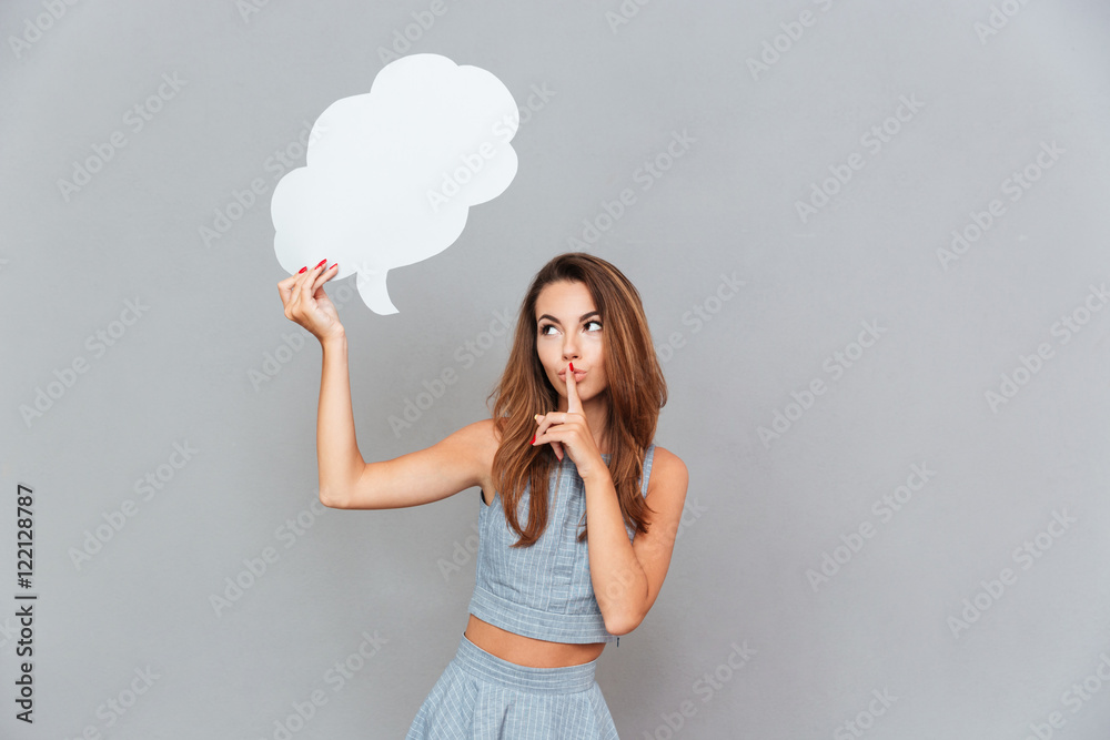 Beautiful woman holding blank speech bubble and showing silence gesture Beautiful woman holding blank speech bubble and showing silence gesture