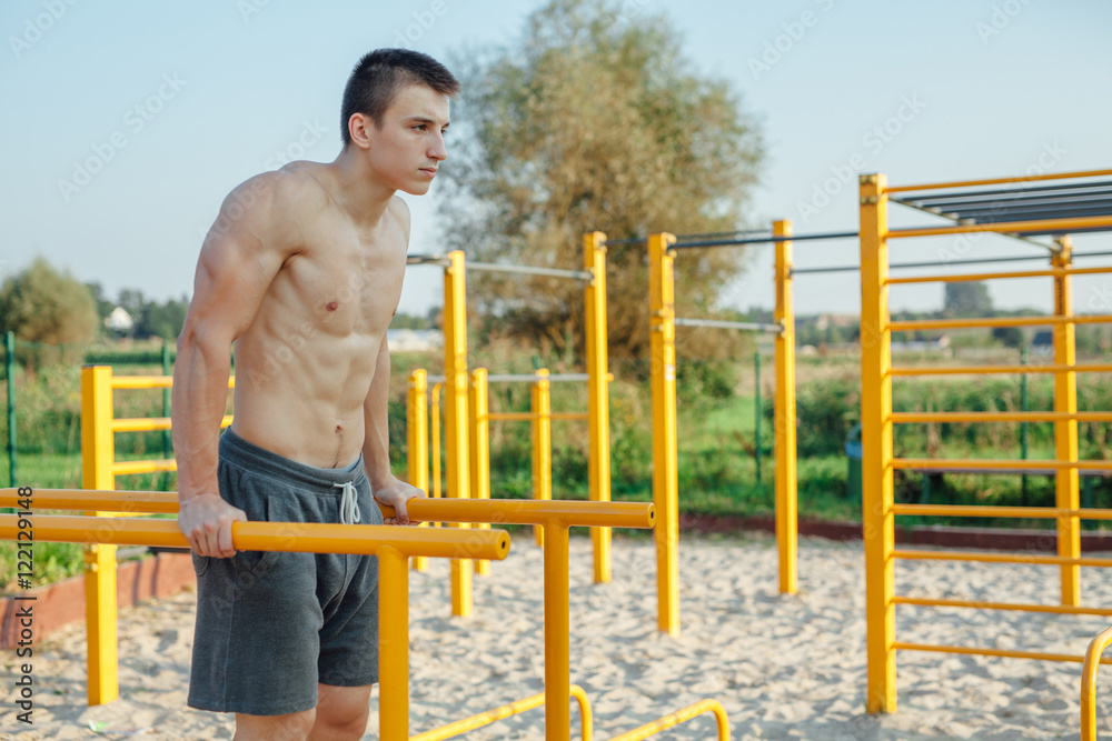 Fototapeta premium Man is pulling up on the bar. Outdoor gym background