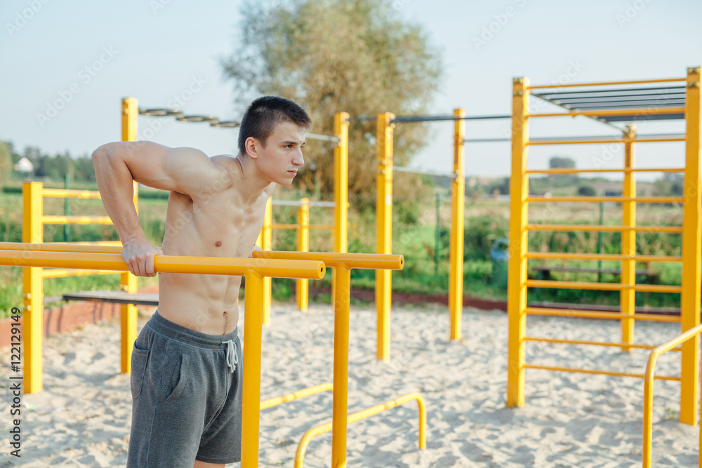 Man is pulling up on the bar. Outdoor gym background