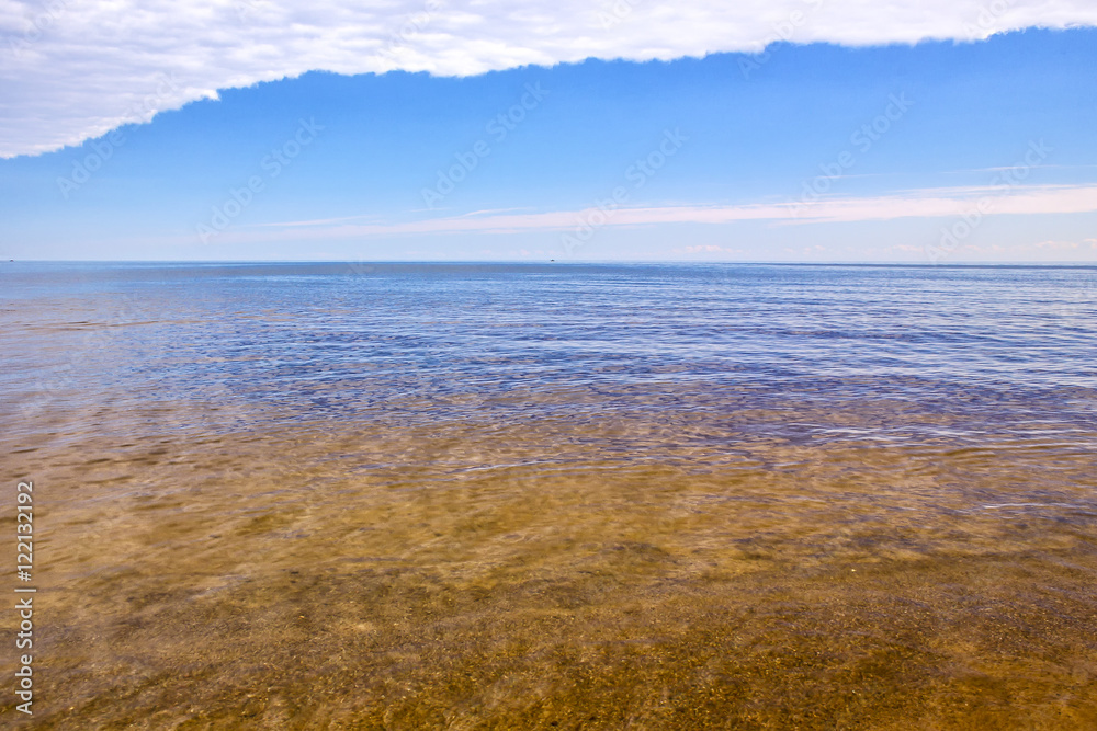 Landscape in the colors of the Russian flag, sandy bottom, water, blue sky and clouds