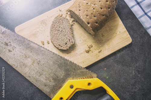 Bild auf Leinwand hard stale bread and cut off a piece of it lie on a wooden cutting board, rusty