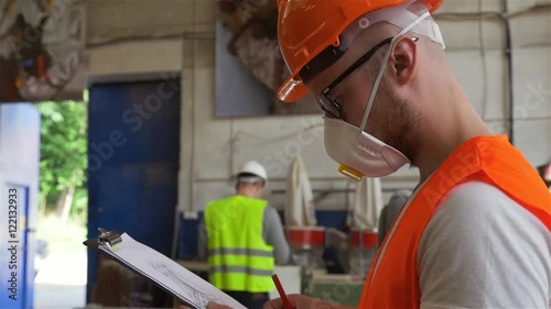 A carpenter in safety mask is writing sth on site plans. photo