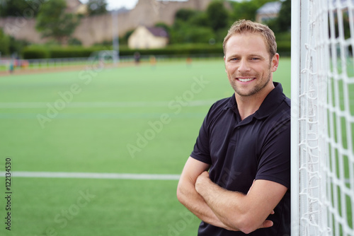 Obraz na płótnie Mężczyzna opiera przeciw futbolowemu celowi na sporta pola ono uśmiecha się
