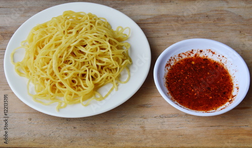 Chinese egg noodle on dish and cayenne pepper sauce