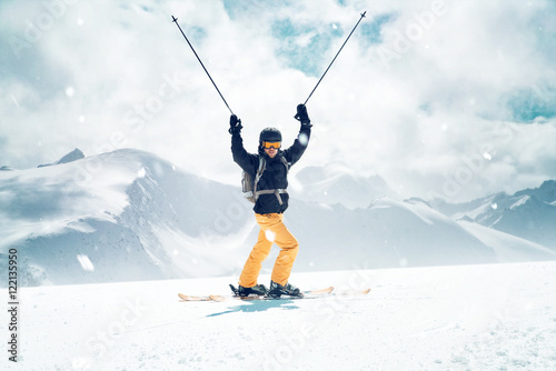 Glücklicher Skifahrer streckt die Skistöcke in die Luft