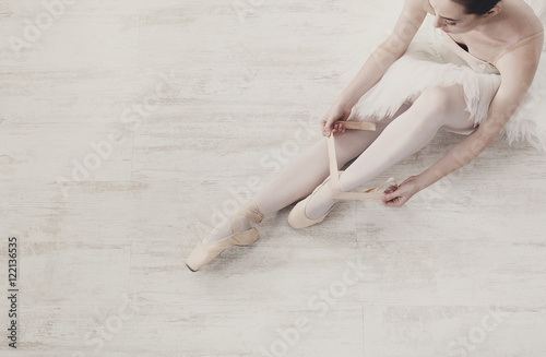 Ballerina puts on pointe ballet shoes, graceful legs