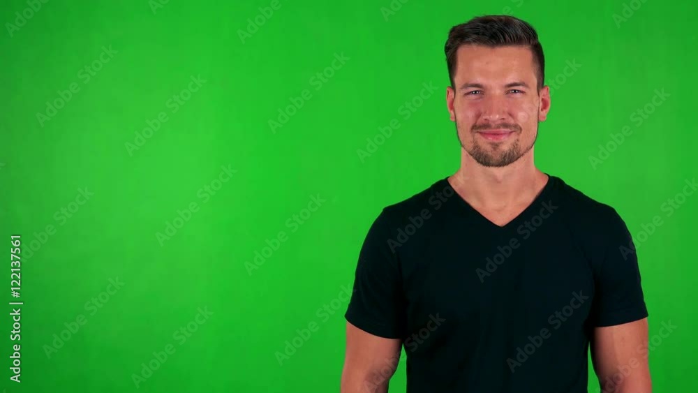 young handsome caucasian man smiles to camera - green screen - studio