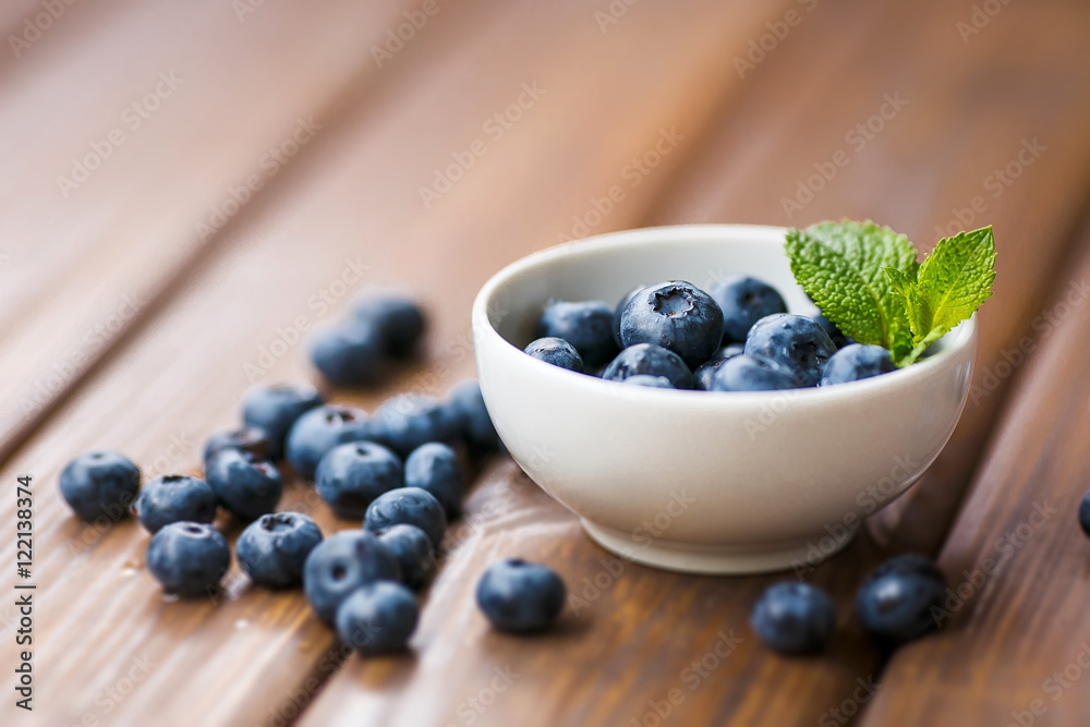 Blueberries in a white cup on a wooden background Blueberries in a white cup on a wooden background