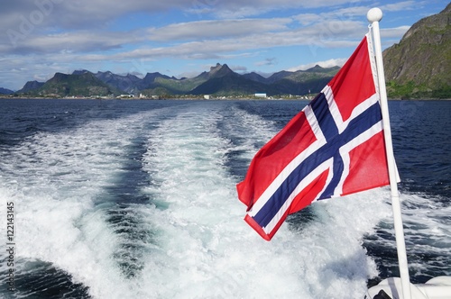 A red and blue Norwegian flag floating over the water from a boat