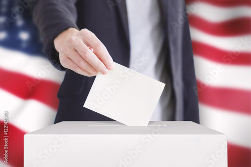 Voting. Man putting a ballot into a voting box with USA flag on background.
