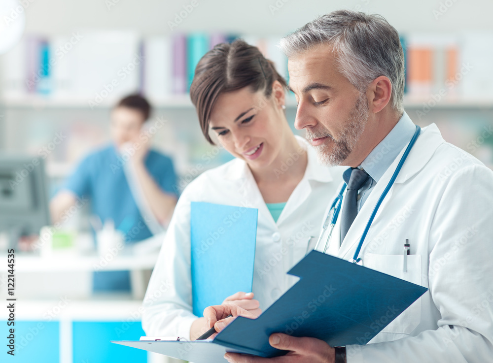 Doctor checking medical records with his assistant Doctor checking medical records with his assistant