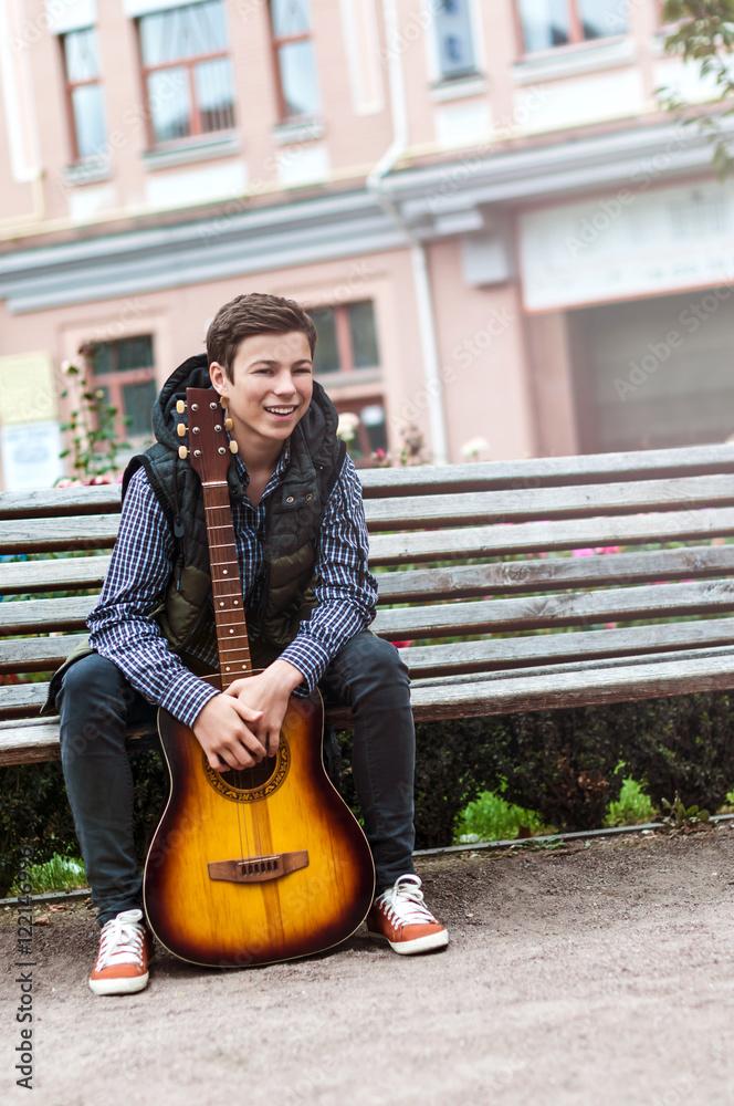 Young man playing on acoustic guitar outdoor