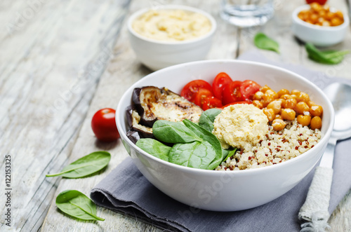 Mediterranean quinoa hummus bowl with eggplants, tomatoes and sp