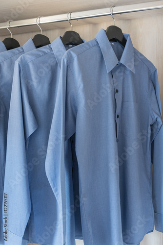 row of blue color shirts hanging on rail